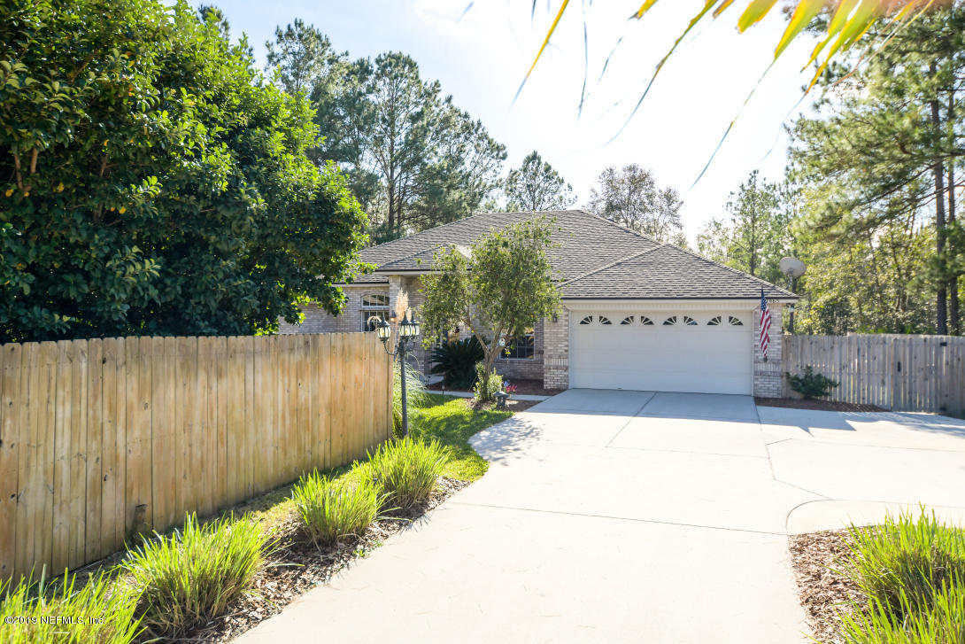 87465 Creekside Drive Yulee, FL 32097 - Photo 4 of 40 a view of a house with a large tree and wooden fence