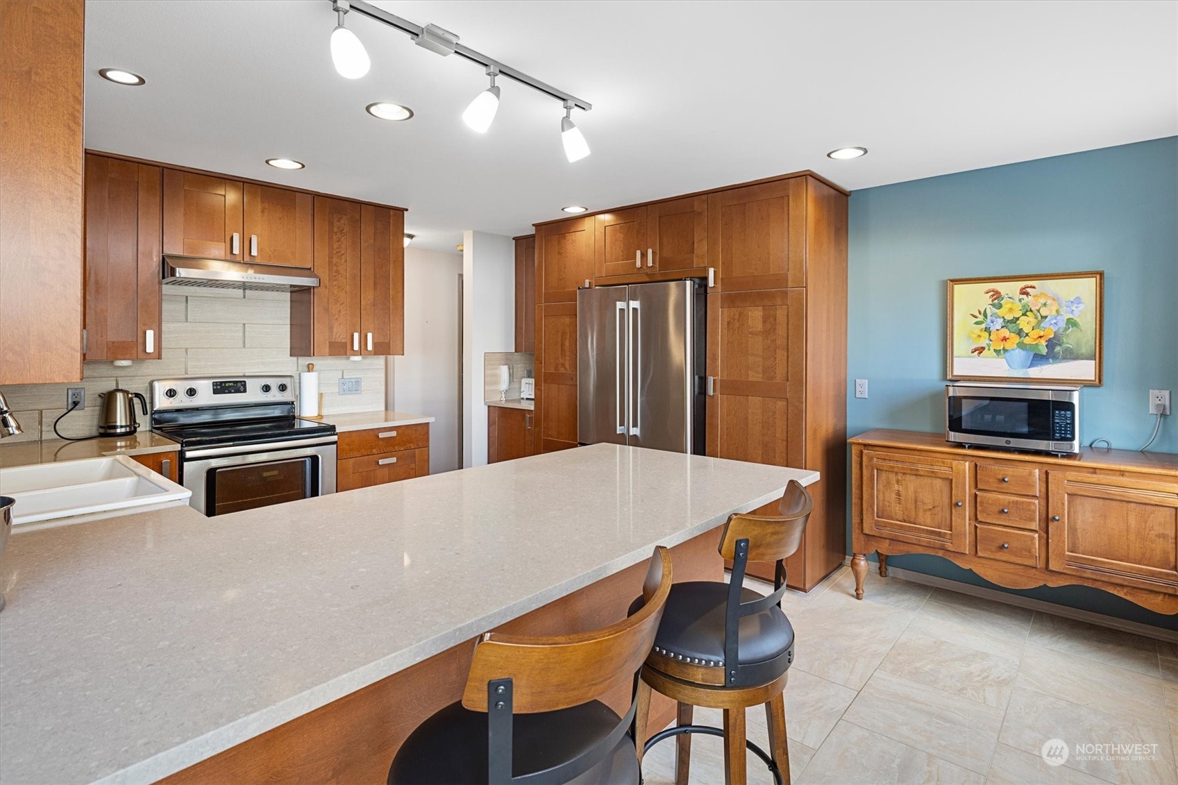 201 3rd Avenue North, Unit 102 Edmonds, WA 98020 - Photo 12 of 39 a kitchen with stainless steel appliances kitchen island granite countertop a refrigerator a stove and a sink with wooden floor