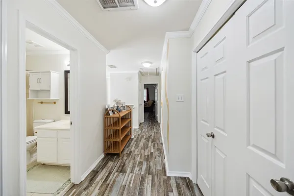 a walk in closet with wooden floor and a bathroom