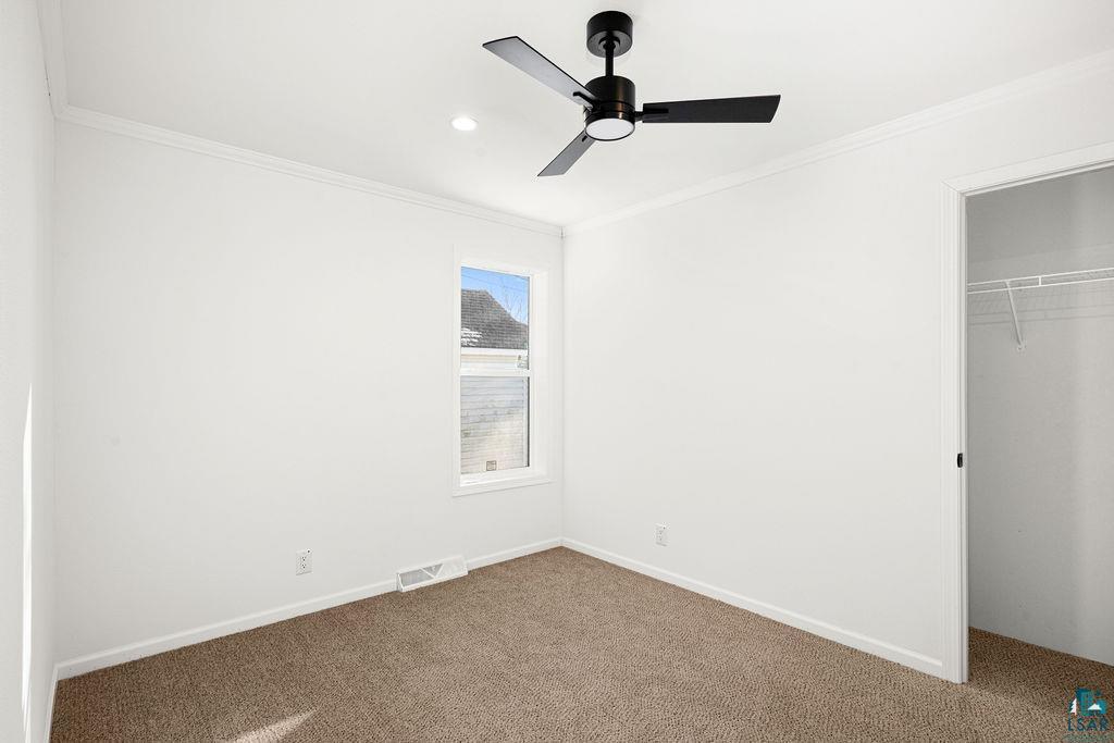 415 Cumming Avenue Superior, WI 54880 - Photo 13 of 26 Unfurnished bedroom with crown molding, a closet, dark colored carpet, and a ceiling fan