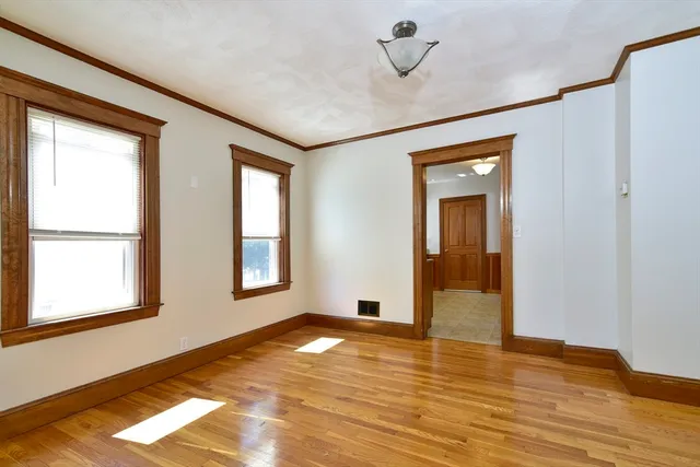 a view of empty room with wooden floor and fan