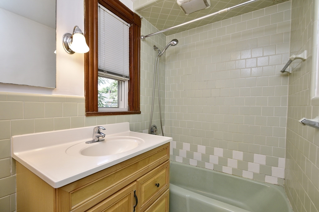 43 Oakridge Street, Unit 2 Boston, MA 02126 - Photo 5 of 8 a bathroom with a sink a mirror and a bathtub