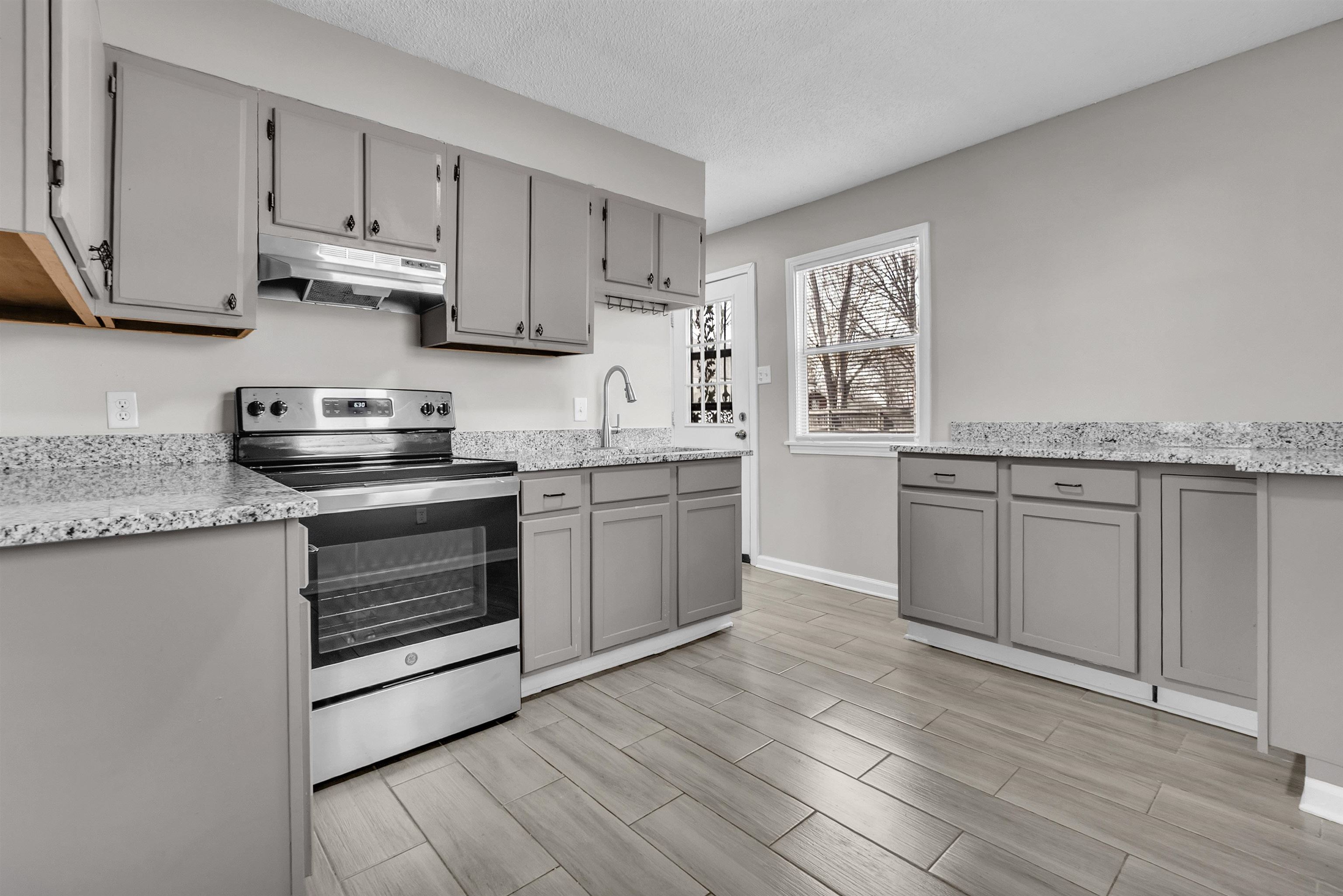 Kitchen featuring gray cabinetry, electric stove, wood finish floors, light stone countertops, and a textured ceiling