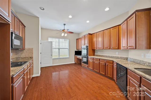 a kitchen with stainless steel appliances granite countertop wooden cabinets a stove top oven a sink and dishwasher