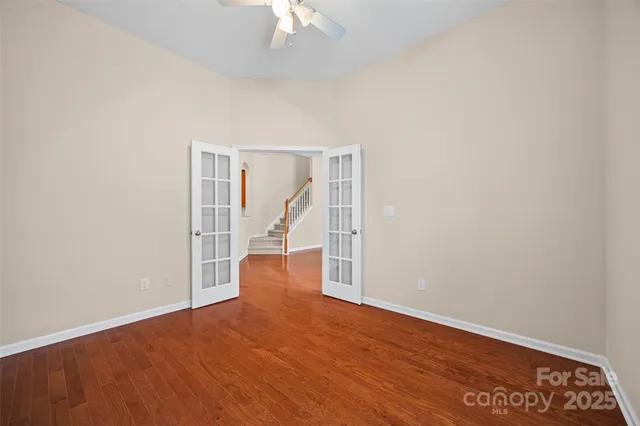 an empty room with wooden floor and chandelier fan