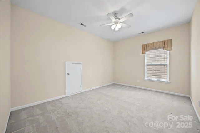 an empty room with a chandelier fan and windows