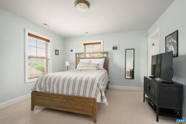 a bedroom with a bed flat screen tv and a window