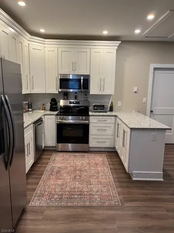 a kitchen with stainless steel appliances granite countertop a stove top oven a sink and a refrigerator