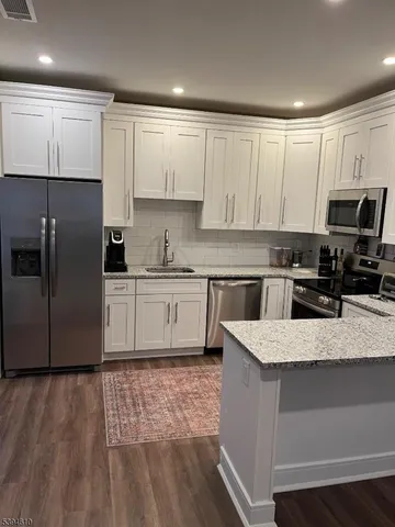 a kitchen with stainless steel appliances granite countertop a sink a stove a refrigerator and cabinets