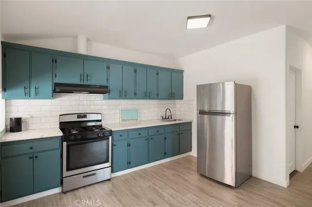 a kitchen with cabinets stainless steel appliances and wooden floor