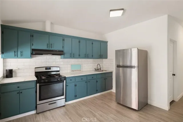 a kitchen with cabinets stainless steel appliances and wooden floor