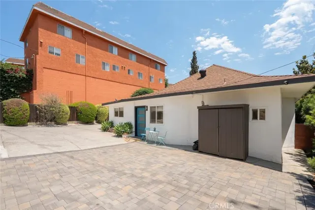 a backyard of a house with table and chairs and potted plants