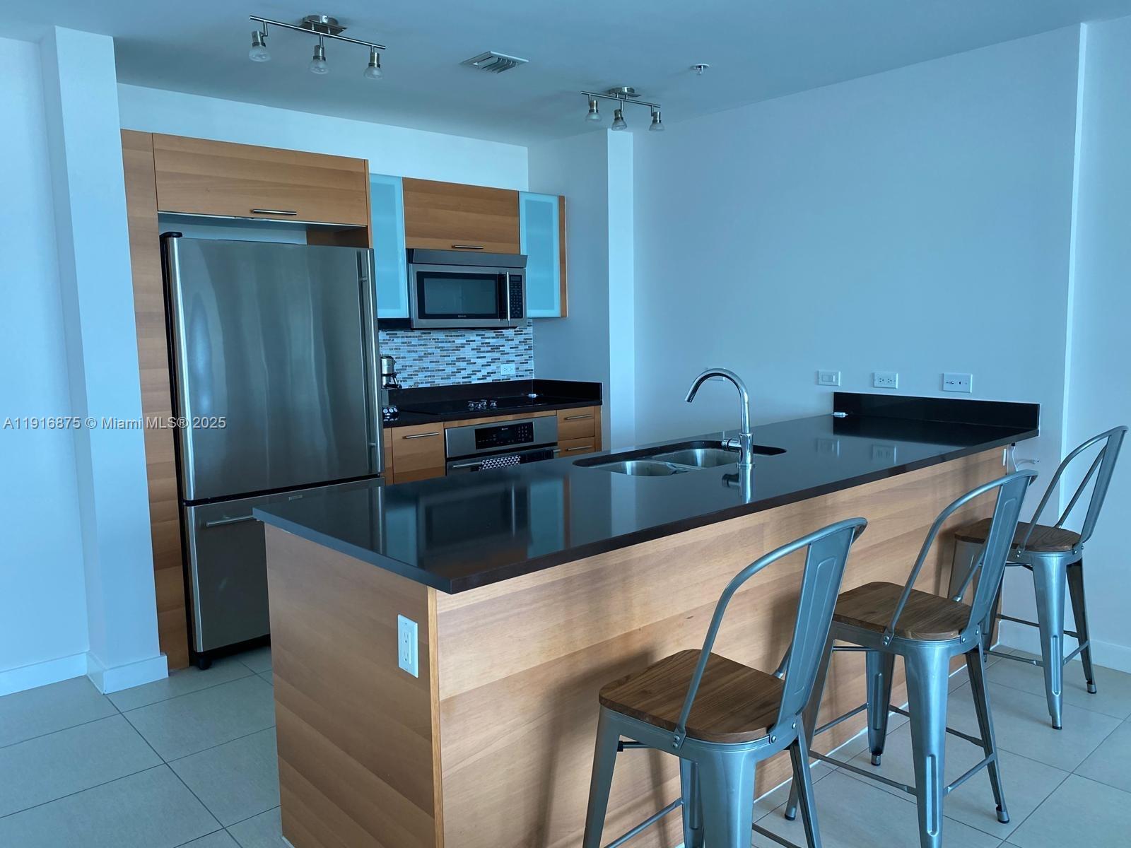 3301 Northeast 1st Avenue, Unit H2913 Miami, FL 33137 - Photo 3 of 11 a kitchen with stainless steel appliances granite countertop a chairs and a refrigerator