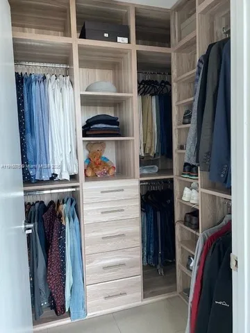 a view of walk in closet with clothes and shoes