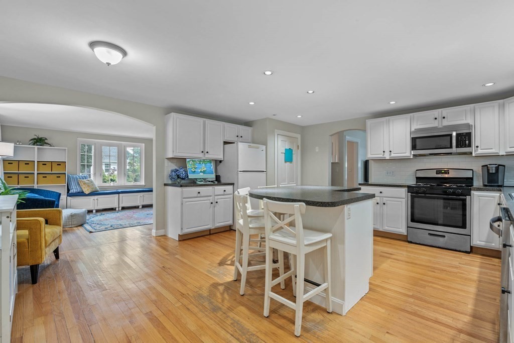 40 Pickwick Road Marblehead, MA 01945 - Photo 11 of 32 a kitchen with stainless steel appliances granite countertop a stove top oven a sink dishwasher a dining table and chairs with wooden floor