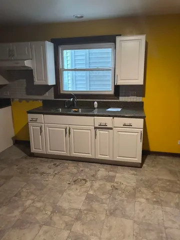 a kitchen with stainless steel appliances a sink a stove a refrigerator a window and cabinets