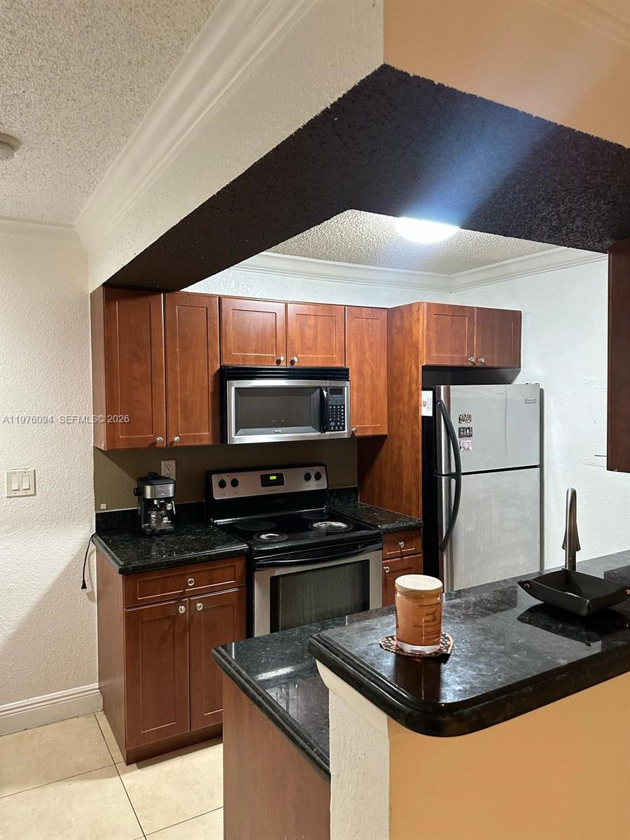15640 Southwest 106th Lane, Unit 903 Miami, FL 33196 - Photo 6 of 8 a kitchen with stainless steel appliances kitchen island granite countertop a stove and a sink