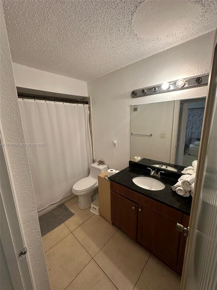 15640 Southwest 106th Lane, Unit 903 Miami, FL 33196 - Photo 7 of 8 a bathroom with a granite countertop sink toilet and shower