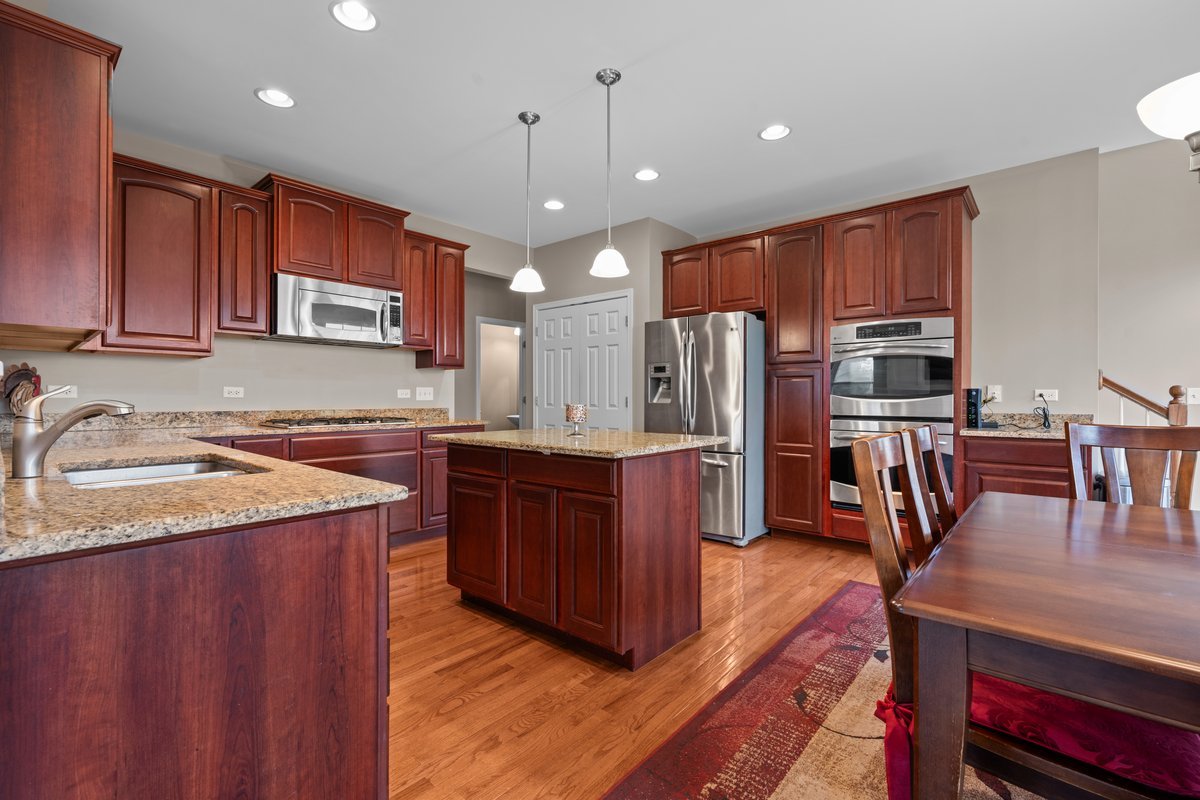 312 Monument Road Elgin, IL 60124 - Photo 8 of 44 a kitchen with stainless steel appliances granite countertop a refrigerator a sink dishwasher a stove and a dining table with wooden cabinet