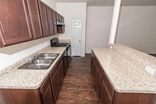 a kitchen with granite countertop sink stove and cabinets