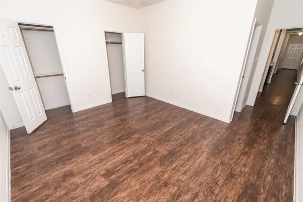 an empty room with wooden floor and a hallway