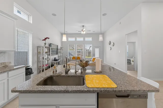 a kitchen with a granite countertop sink and natural light