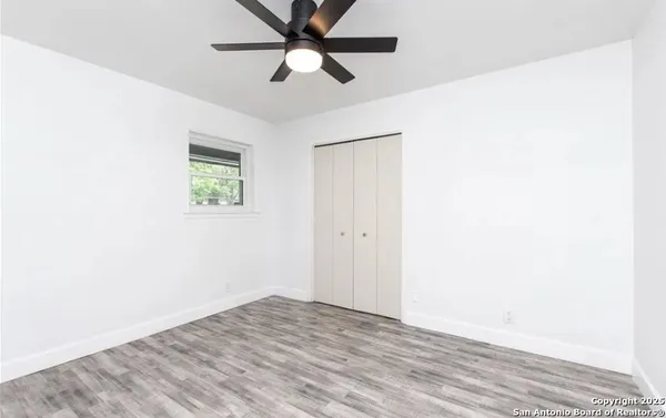an empty room with a window and a fan