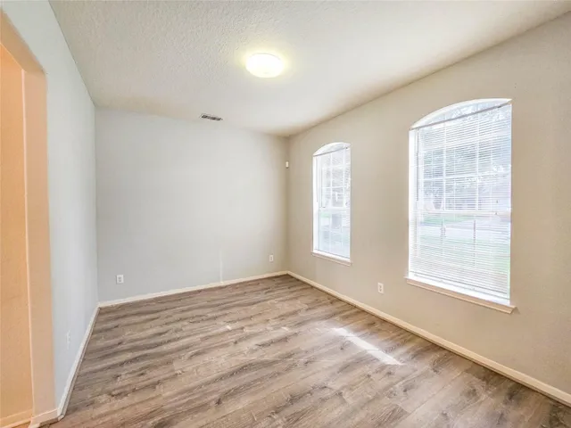 an empty room with wooden floor and windows