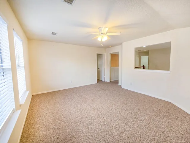 an empty room with a chandelier fan and windows