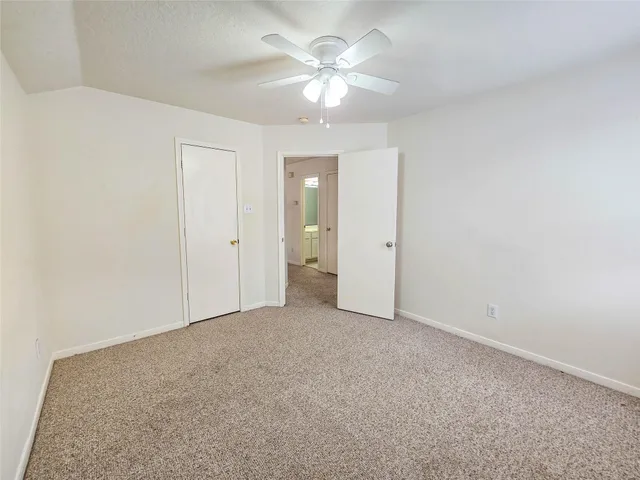 an empty room with chandelier fan and closet area