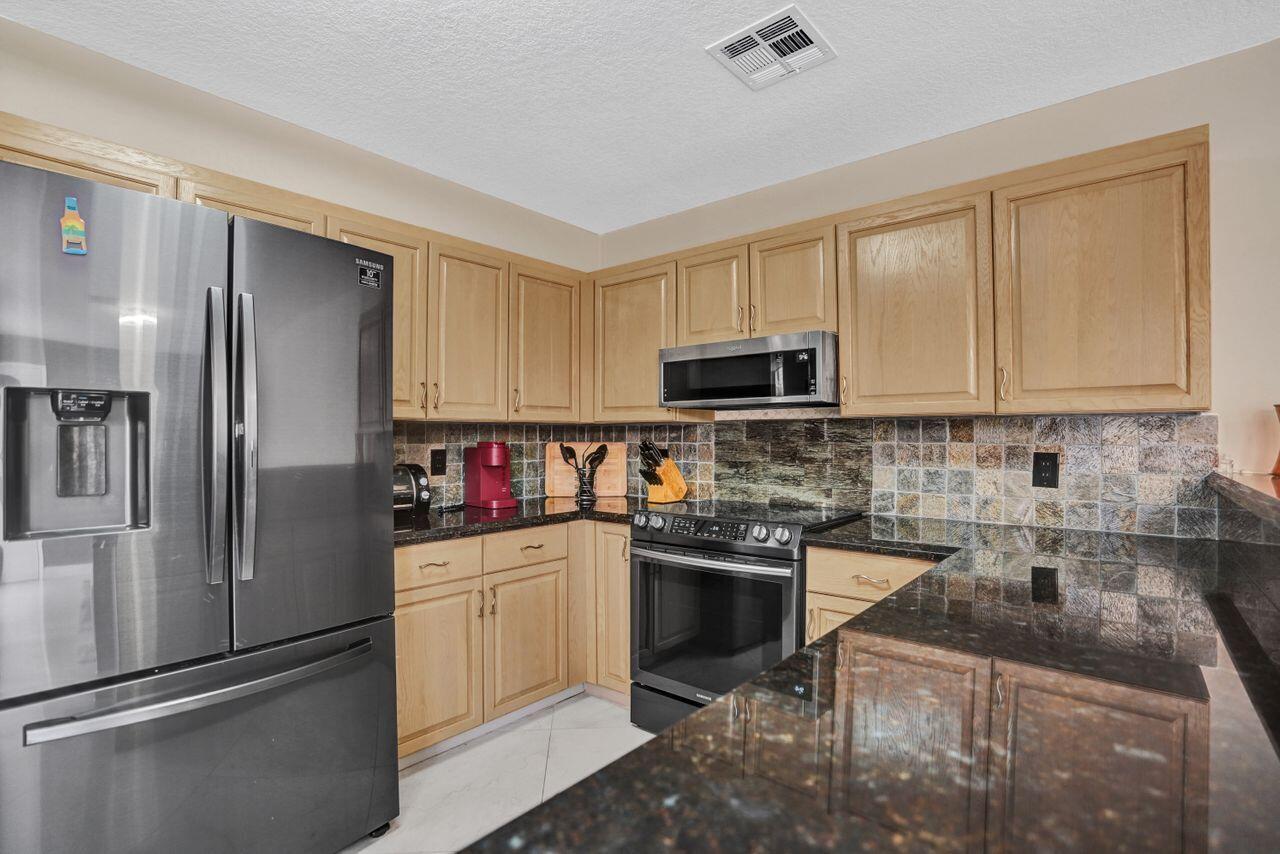 5465 Monterey Circle, Unit D Delray Beach, FL 33484 - Photo 26 of 67 a kitchen with stainless steel appliances granite countertop a refrigerator stove and sink