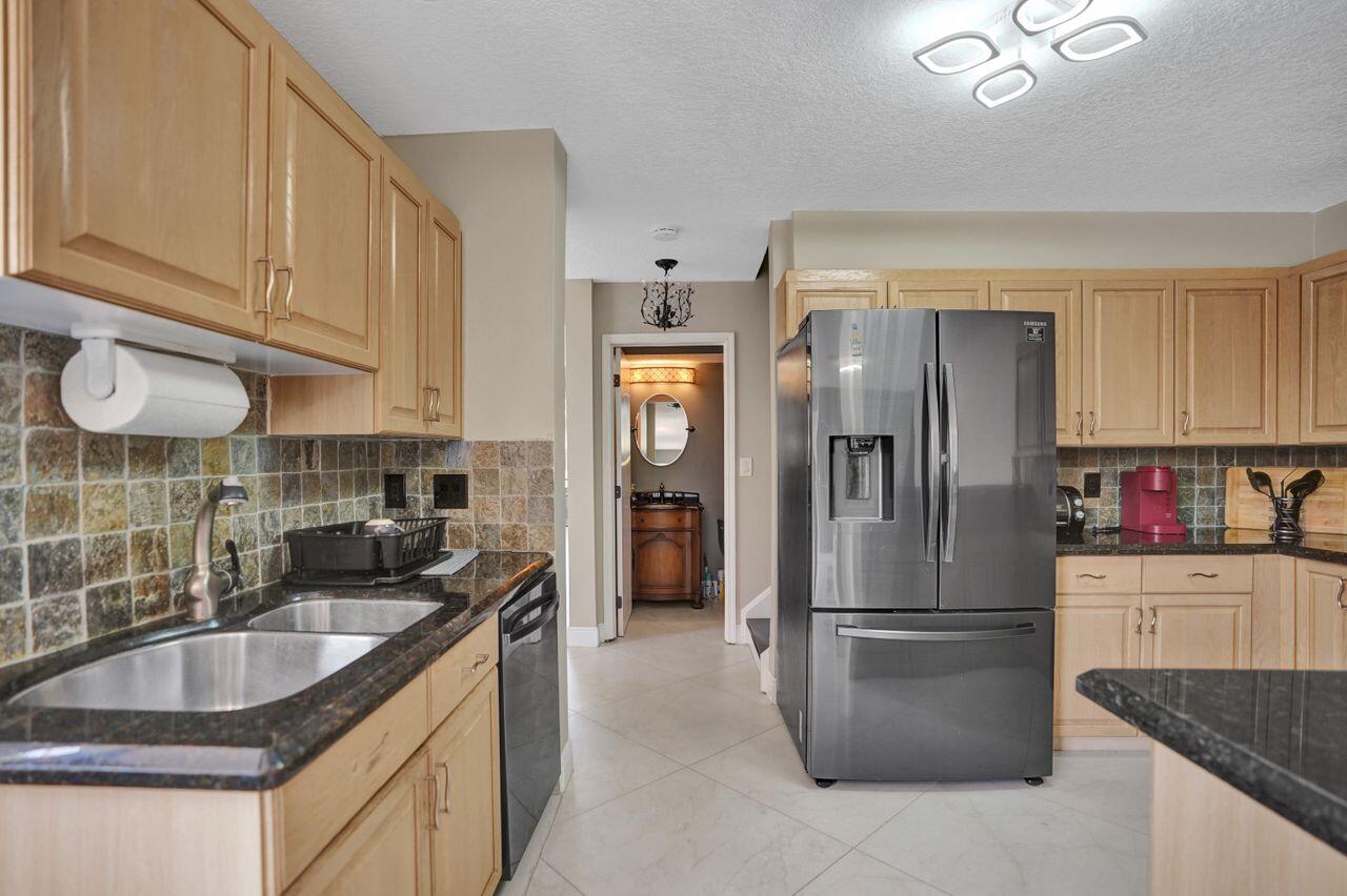 5465 Monterey Circle, Unit D Delray Beach, FL 33484 - Photo 28 of 67 a kitchen with stainless steel appliances granite countertop a refrigerator a sink a stove and a sink