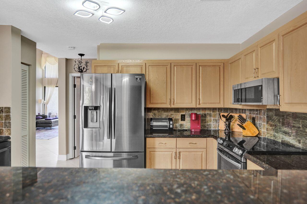 5465 Monterey Circle, Unit D Delray Beach, FL 33484 - Photo 30 of 67 a kitchen with stainless steel appliances granite countertop a refrigerator and a stove top oven