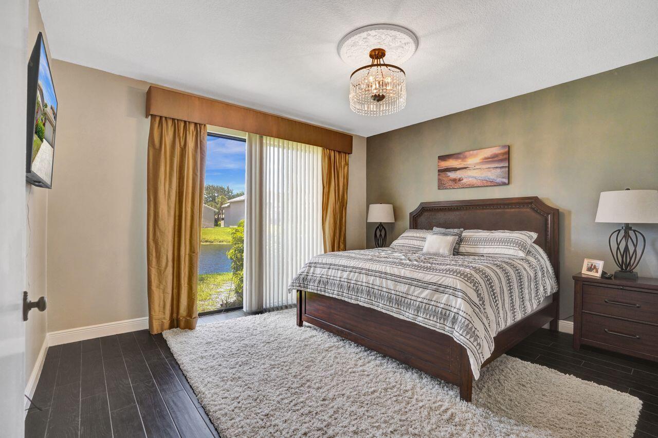 5465 Monterey Circle, Unit D Delray Beach, FL 33484 - Photo 40 of 67 a bedroom with a large bed and a chandelier
