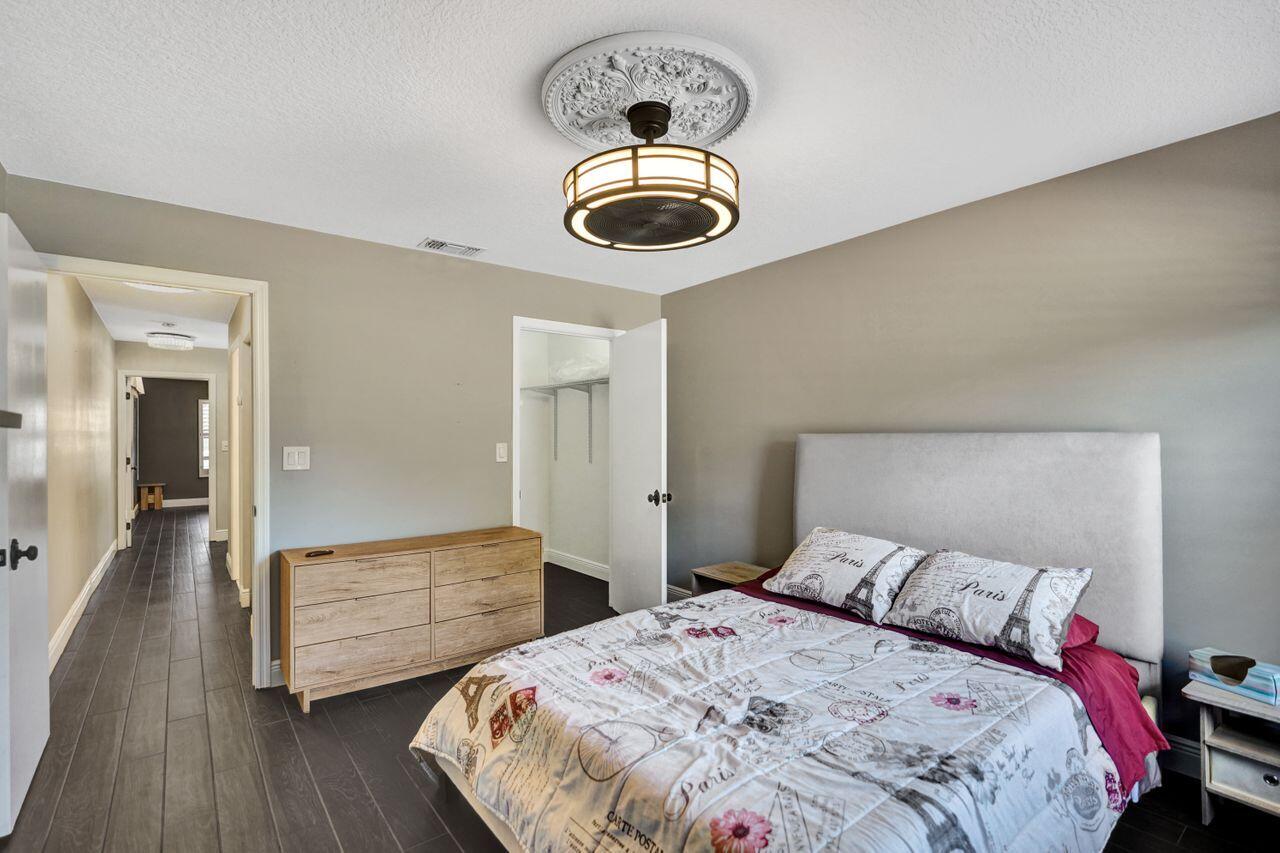 5465 Monterey Circle, Unit D Delray Beach, FL 33484 - Photo 50 of 67 a bedroom with a bed and a chandelier