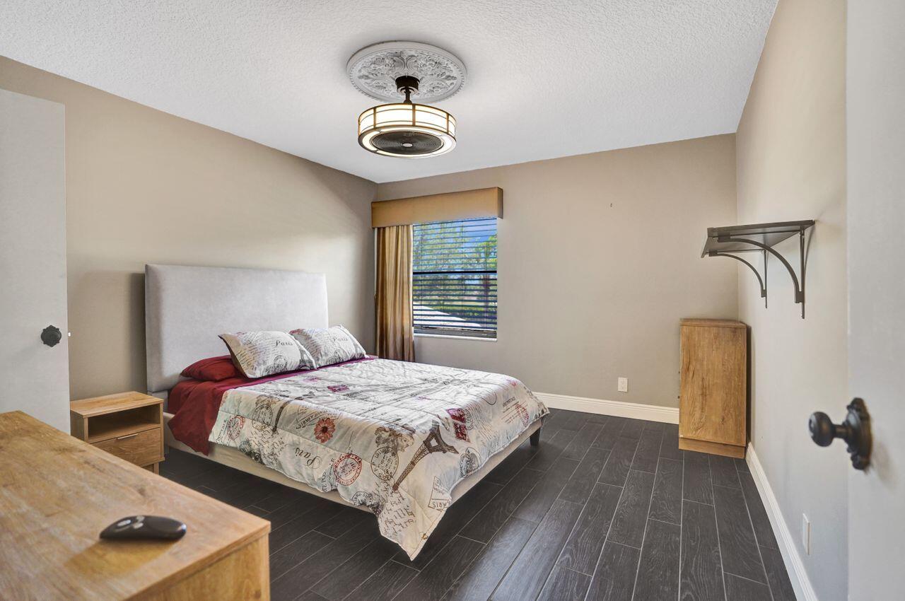 5465 Monterey Circle, Unit D Delray Beach, FL 33484 - Photo 51 of 67 a bedroom with a bed and wooden floor