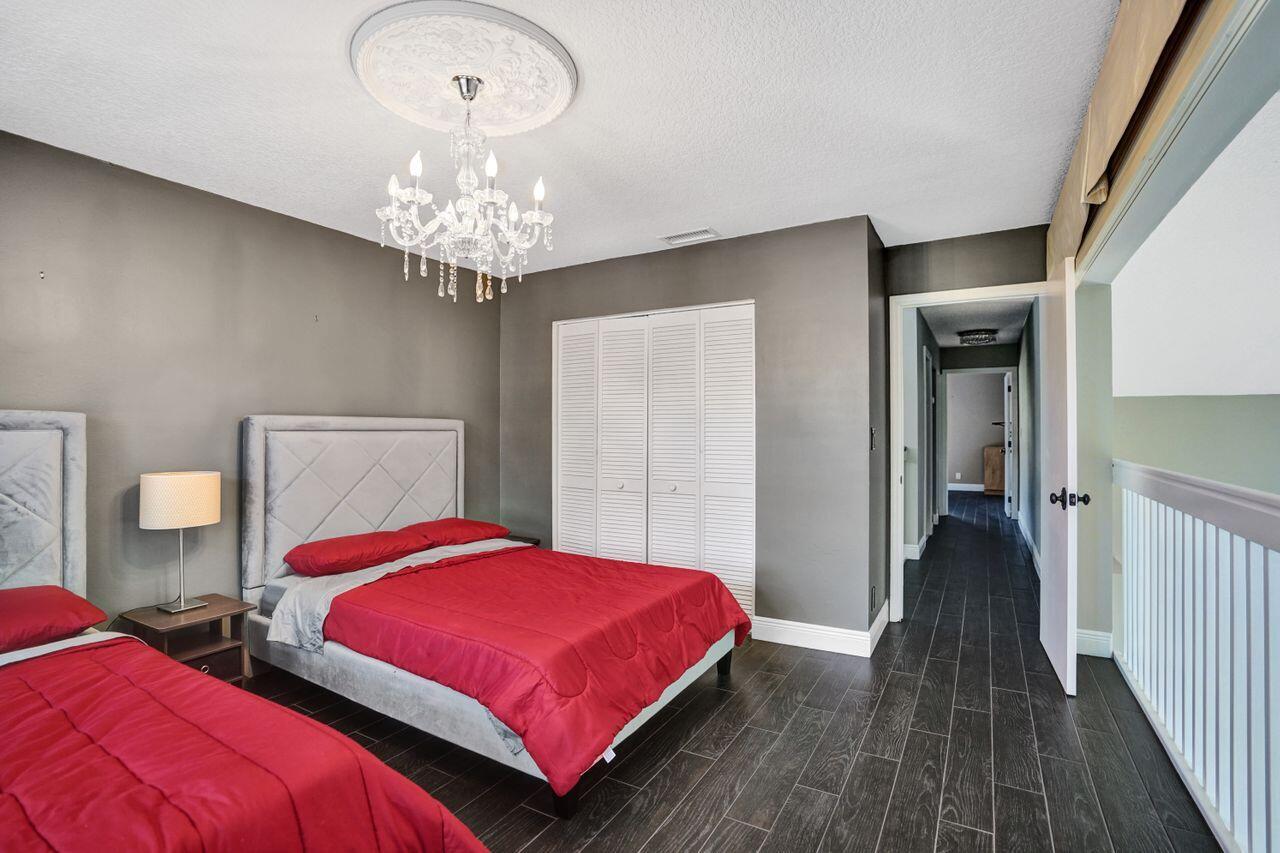 5465 Monterey Circle, Unit D Delray Beach, FL 33484 - Photo 60 of 67 a bedroom with two beds and a chandelier