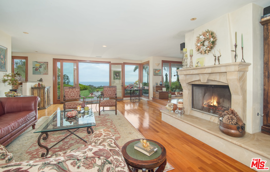 29660 Harvester Road Malibu, CA 90265 - Photo 3 of 32 a living room with furniture a fireplace and a floor to ceiling window