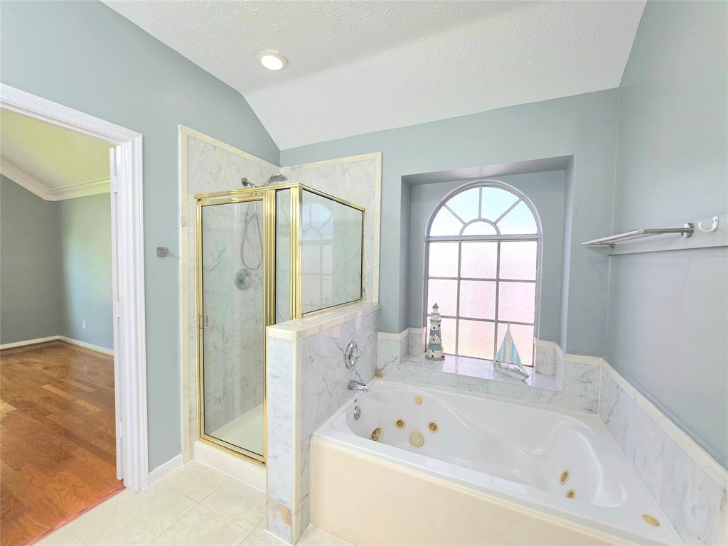 13618 Sablegrove Lane Houston, TX 77014 - Photo 17 of 30 a bathroom with a bathtub a shower and a window