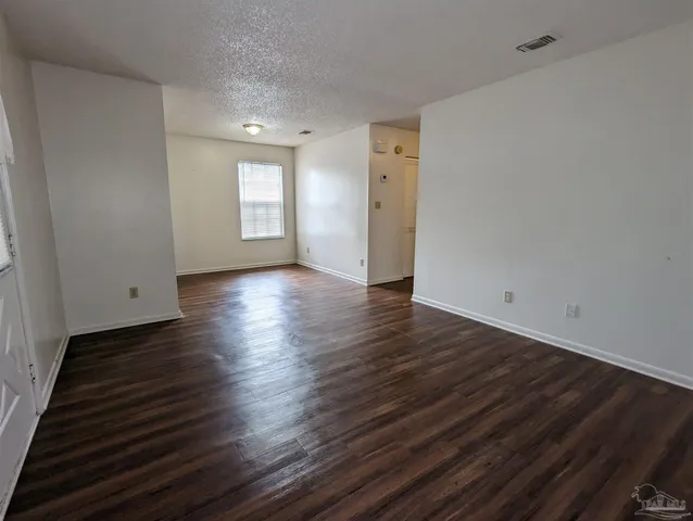 a view of an empty room with window and wooden floor