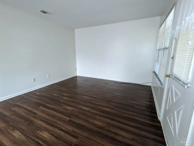 a view of an empty room with wooden floor and stairs