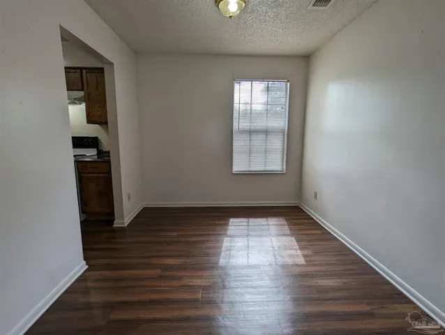 an empty room with wooden floor closet and windows