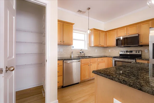 a kitchen with stainless steel appliances granite countertop a sink a stove and a refrigerator
