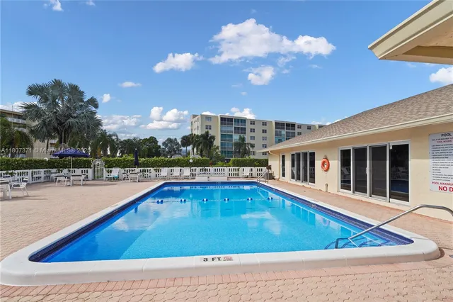 a view of swimming pool on a sunny day with lawn chairs