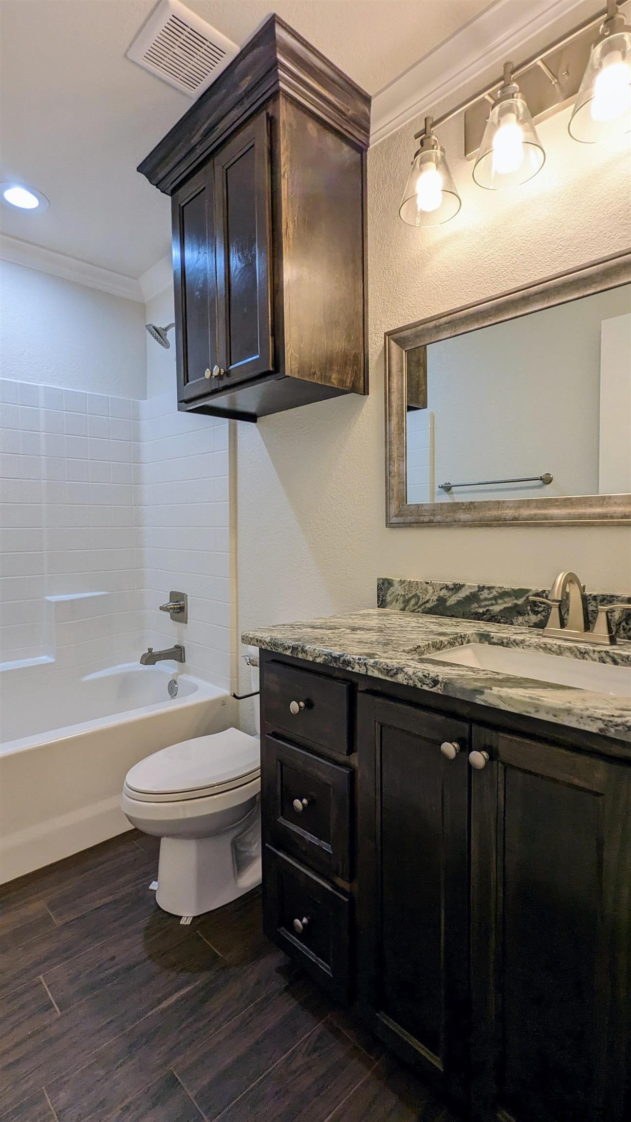 11086 County Road 167, Unit 11 Tyler, TX 75703 - Photo 15 of 20 a bathroom with a granite countertop toilet a sink and bathtub