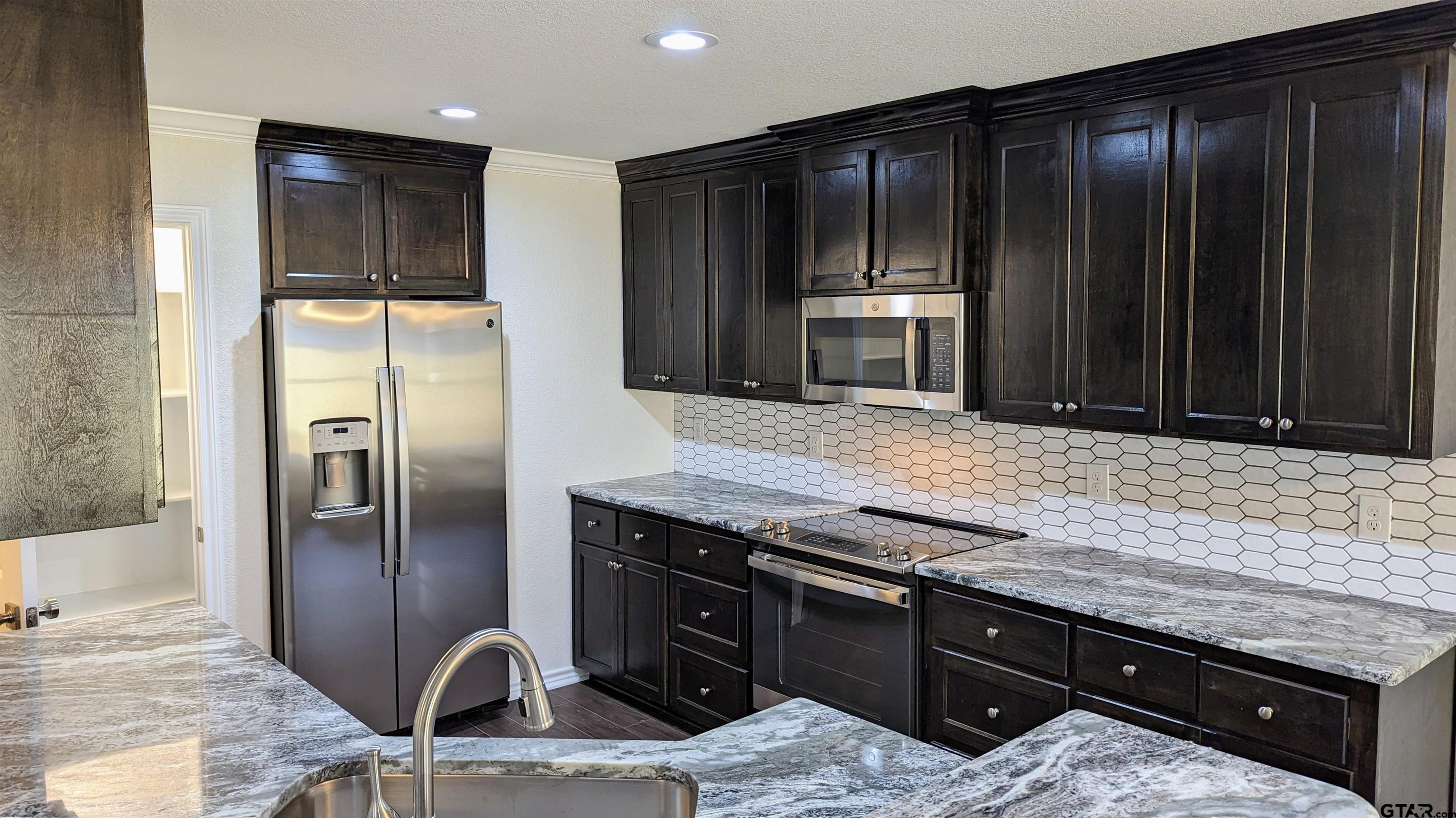 11086 County Road 167, Unit 11 Tyler, TX 75703 - Photo 2 of 20 a kitchen with granite countertop stainless steel appliances and wooden cabinets
