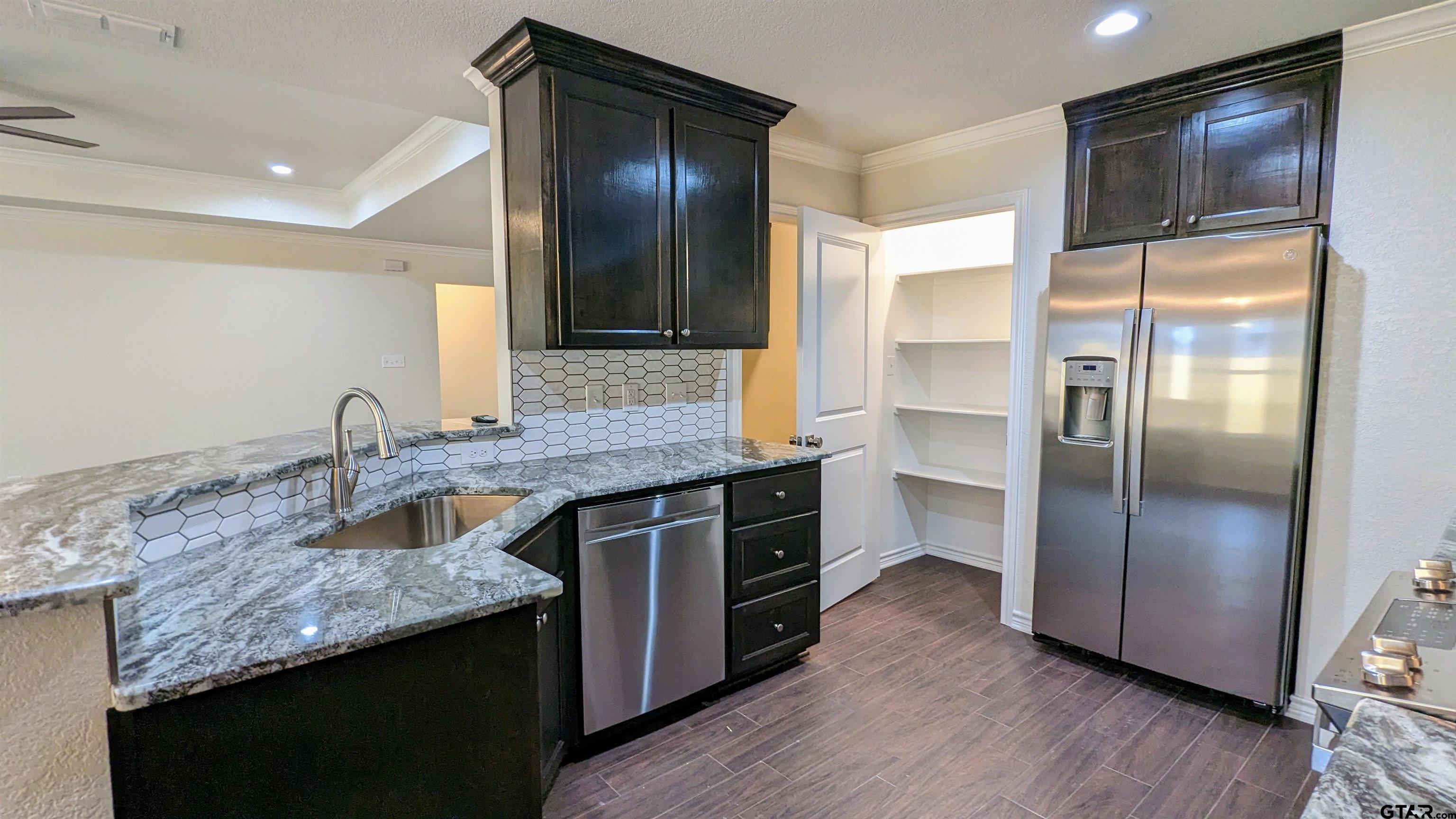11086 County Road 167, Unit 11 Tyler, TX 75703 - Photo 3 of 20 a kitchen with granite countertop stainless steel appliances and wooden cabinets