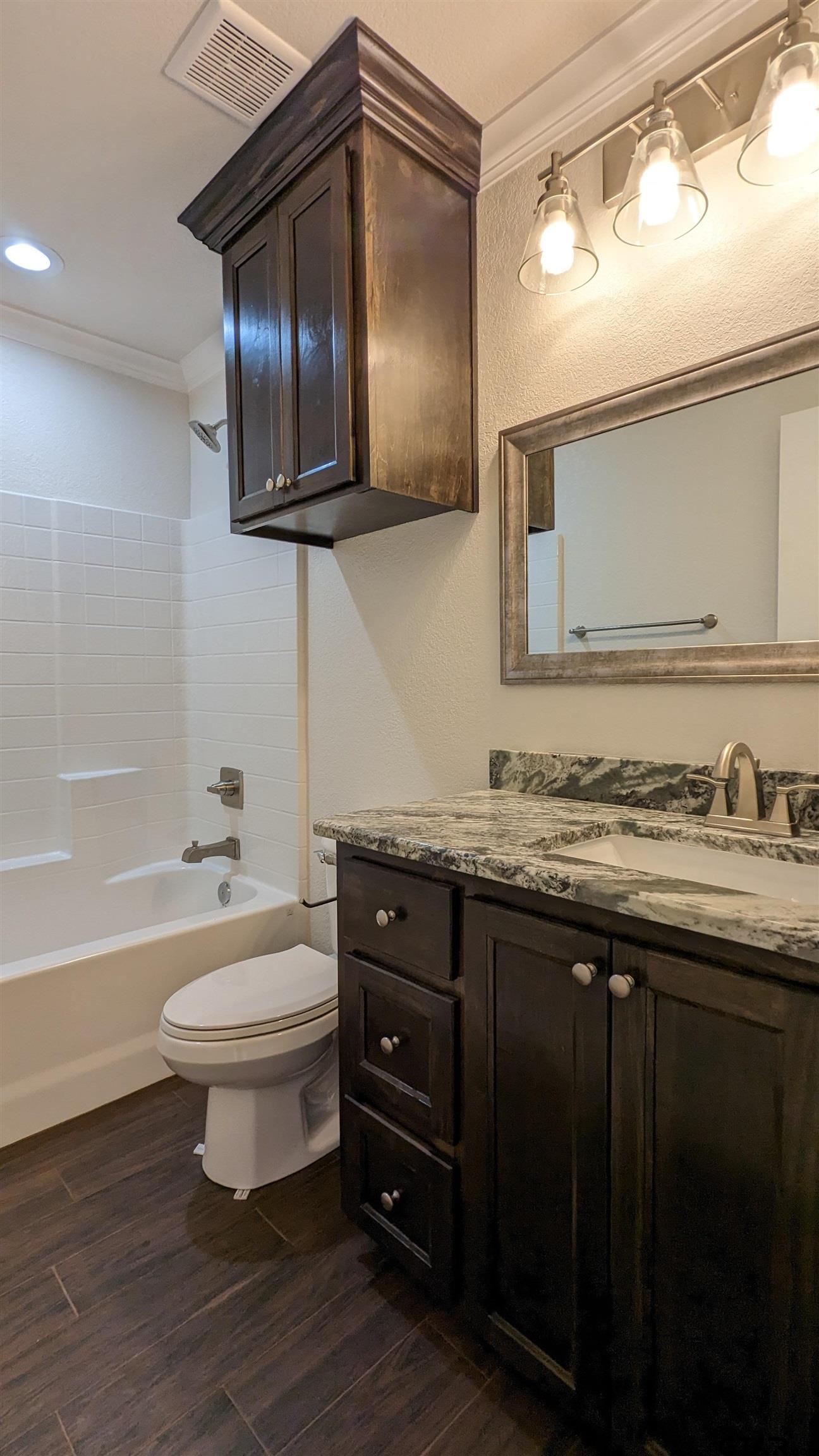 11086 County Road 167, Unit 11 Tyler, TX 75703 - Photo 5 of 20 a bathroom with a granite countertop toilet a sink and bathtub