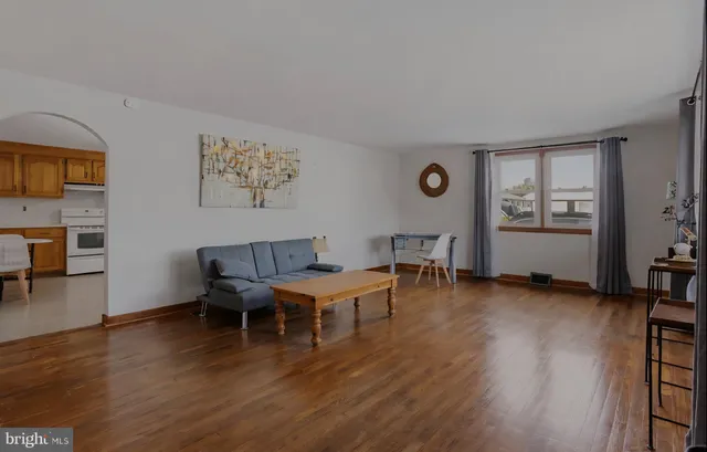 a view of an empty room with wooden floor and a ceiling fan