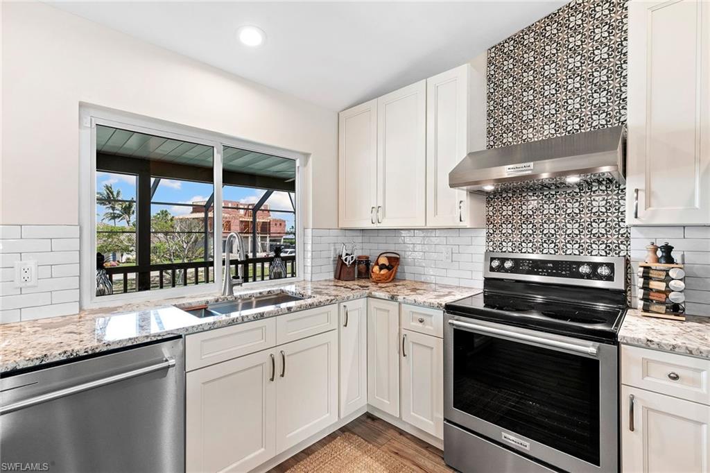 21531 Madera Road Fort Myers Beach, FL 33931 - Photo 10 of 49 a kitchen with stainless steel appliances white cabinets and a stove top oven